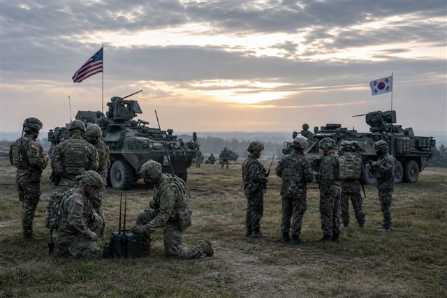 Allied soldiers and armored vehicles on a training field suggesting a joint military exercise
